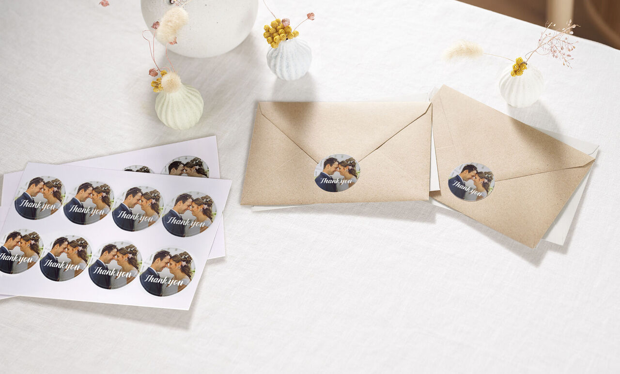 Deux enveloppes marron avec des autocollants Thank You ronds et cartes tamponnées sur une table.