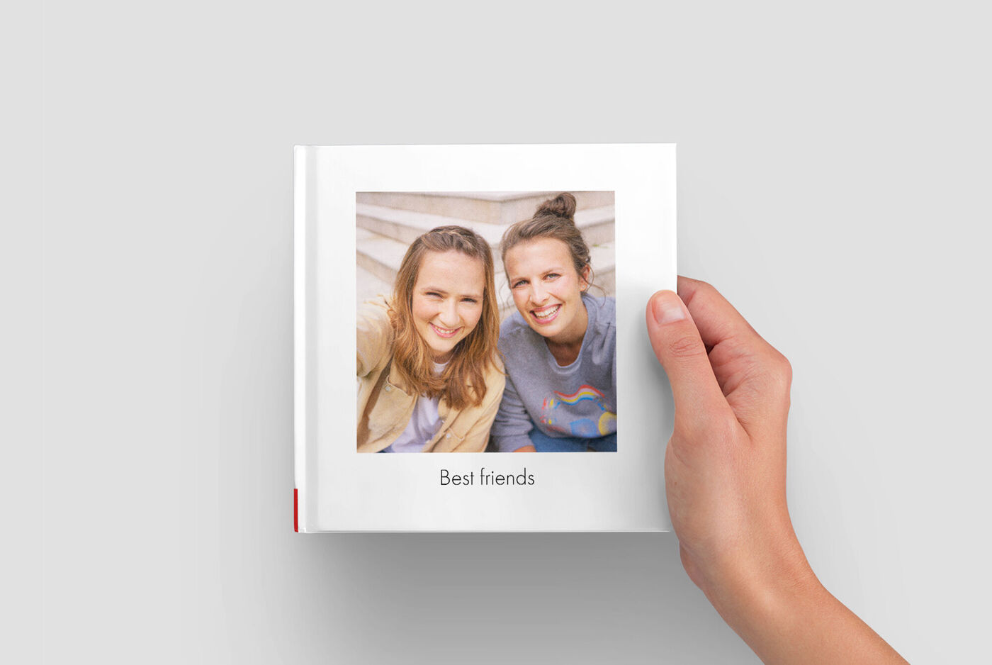 Jeune femme tenant un album CEWE intitulé « Meilleurs amis »