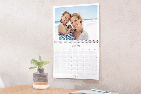 Calendrier photo double-page ouvert sur le mois de juillet et accroché au mur