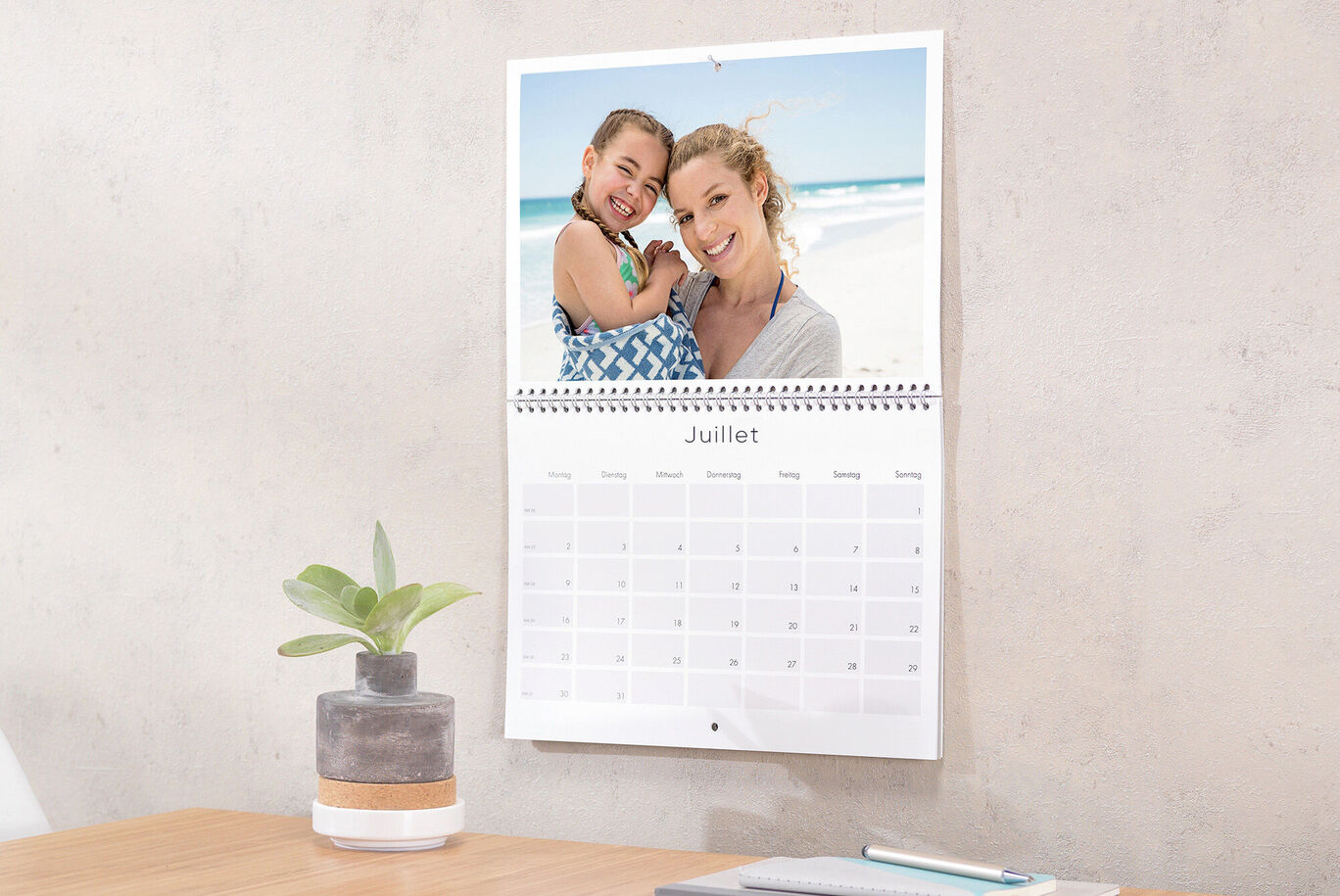 Calendrier photo double-page ouvert sur le mois de juillet et accroché au mur