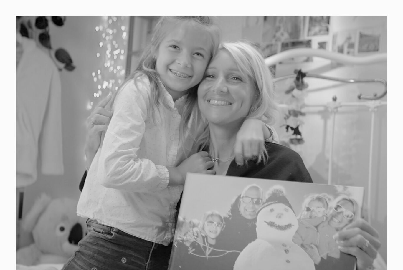 Un enfant étreint un adulte qui tient une affiche avec des motifs de Noël