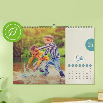 Une page de calendrier montre deux enfants jouant joyeusement dans l'eau avec un bateau jouet.