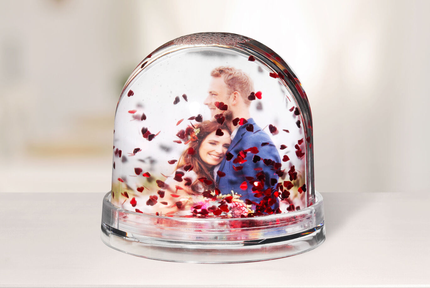 Un globe en verre rempli de confettis en cœur montrant une scène romantique.
