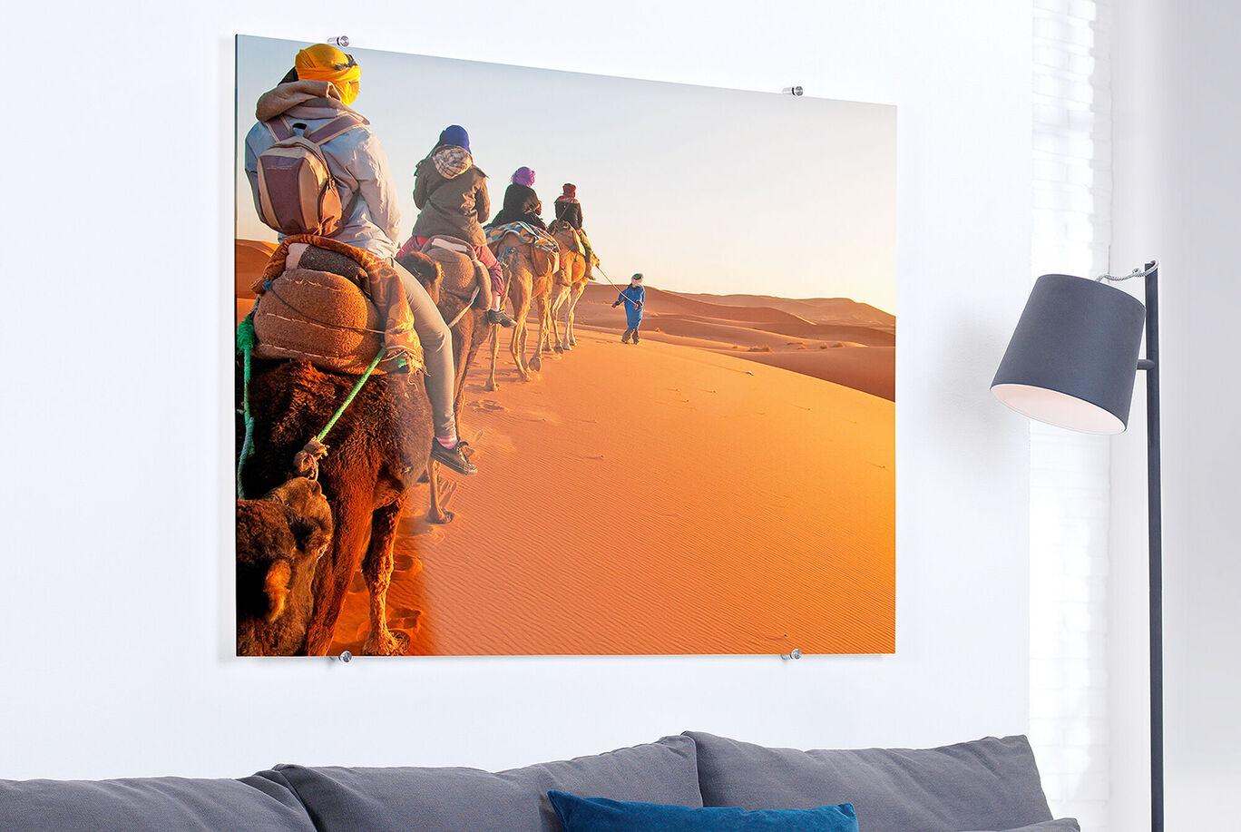 Six cavaliers montent des chameaux sur une dune de sable orange dans le désert