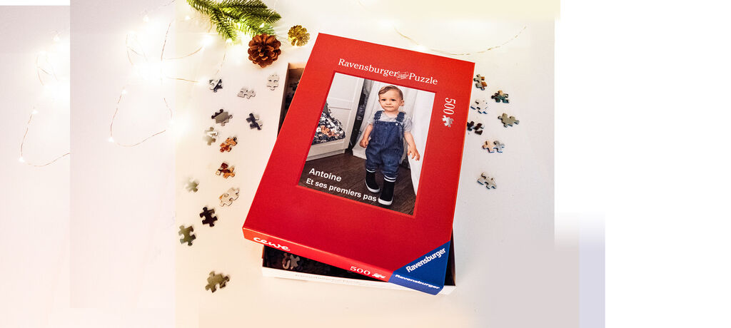 Une boîte de puzzle rouge avec une image d'un enfant souriant en salopette bleue appelé Antoine.