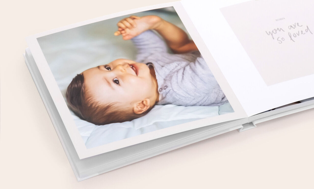 Album photo carré ouvert avec la photo d'un bébé souriant