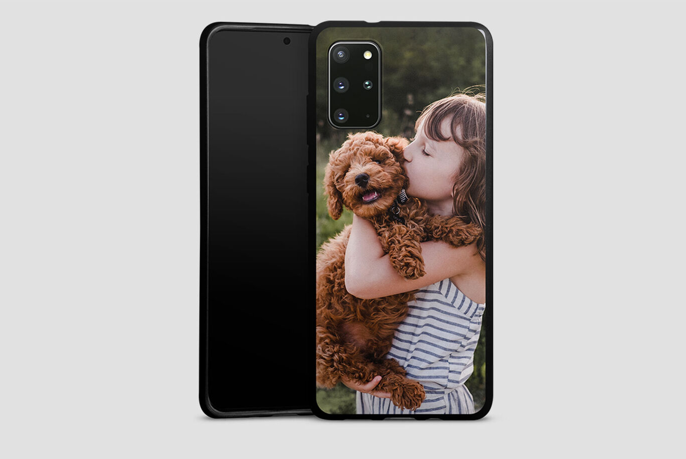 Une fille tient un chien marron et bouclé dans ses bras et sourit avec bonheur.