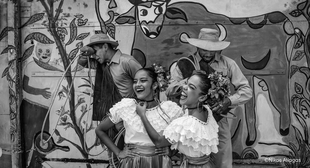 Un groupe de personnes échangent des fleurs devant une peinture murale colorée
