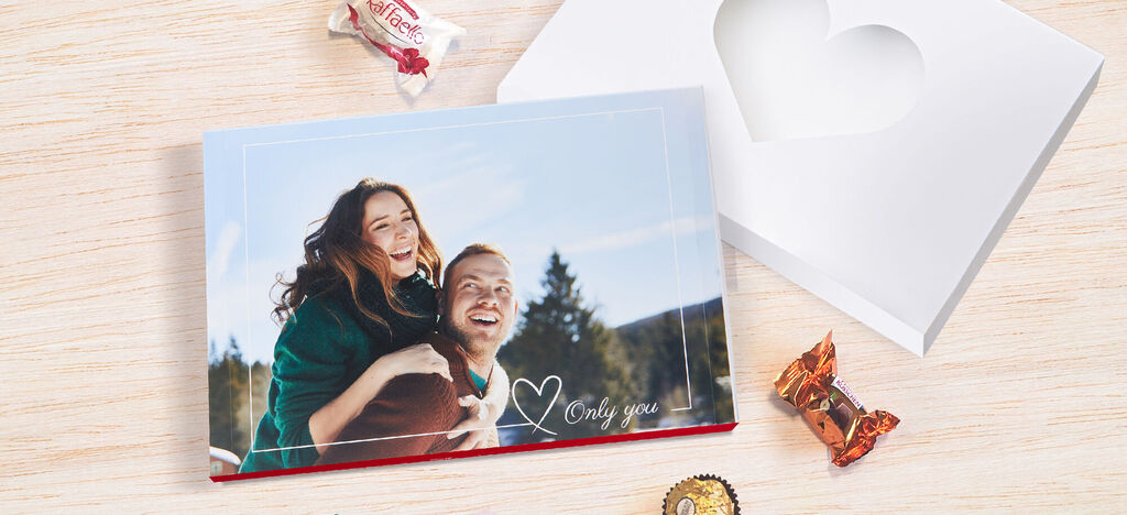 Un album photo CEWE sur une table avec des friandises et une boîte en forme de coeur.