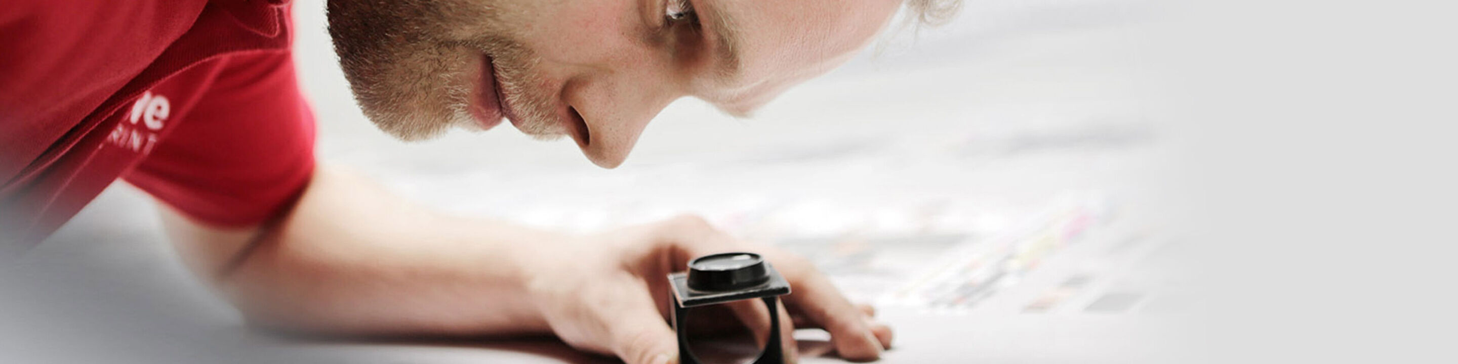 Un employé de CEWE vérifie soigneusement l'impression d'une photo avec une loupe