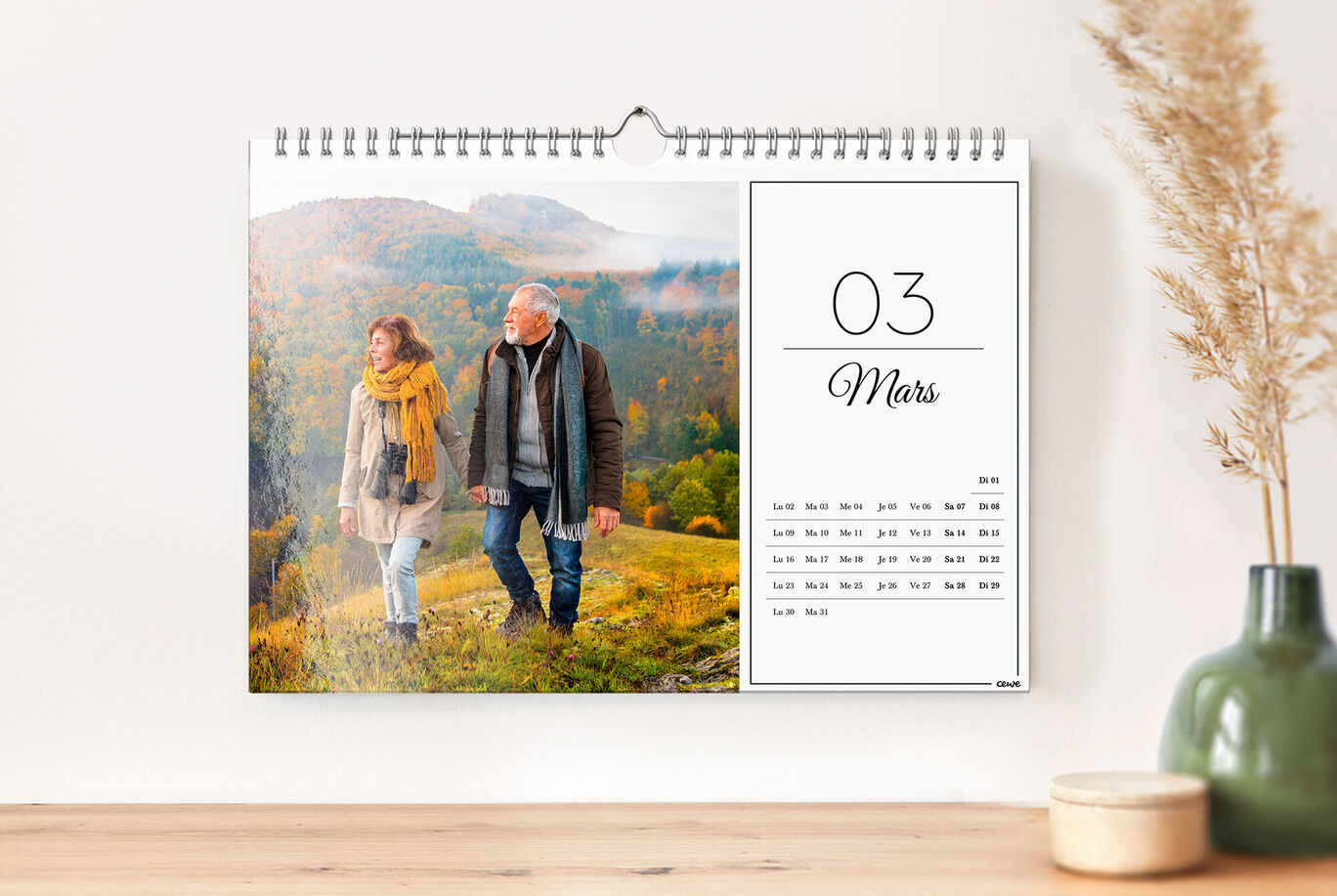 Une page de calendrier montre un couple marchant main dans la main dans un paysage automnal coloré. Le "03" et le mois "mars" sont bien lisibles.