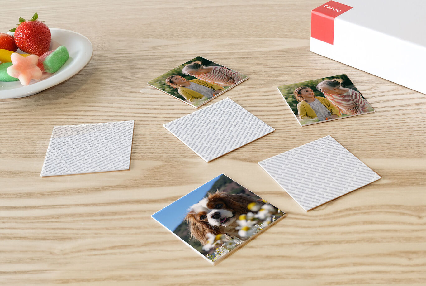 Cinq cartes photo sont posées sur une table en bois clair. On y voit un chien, une famille joyeuse et une assiette de douceurs.