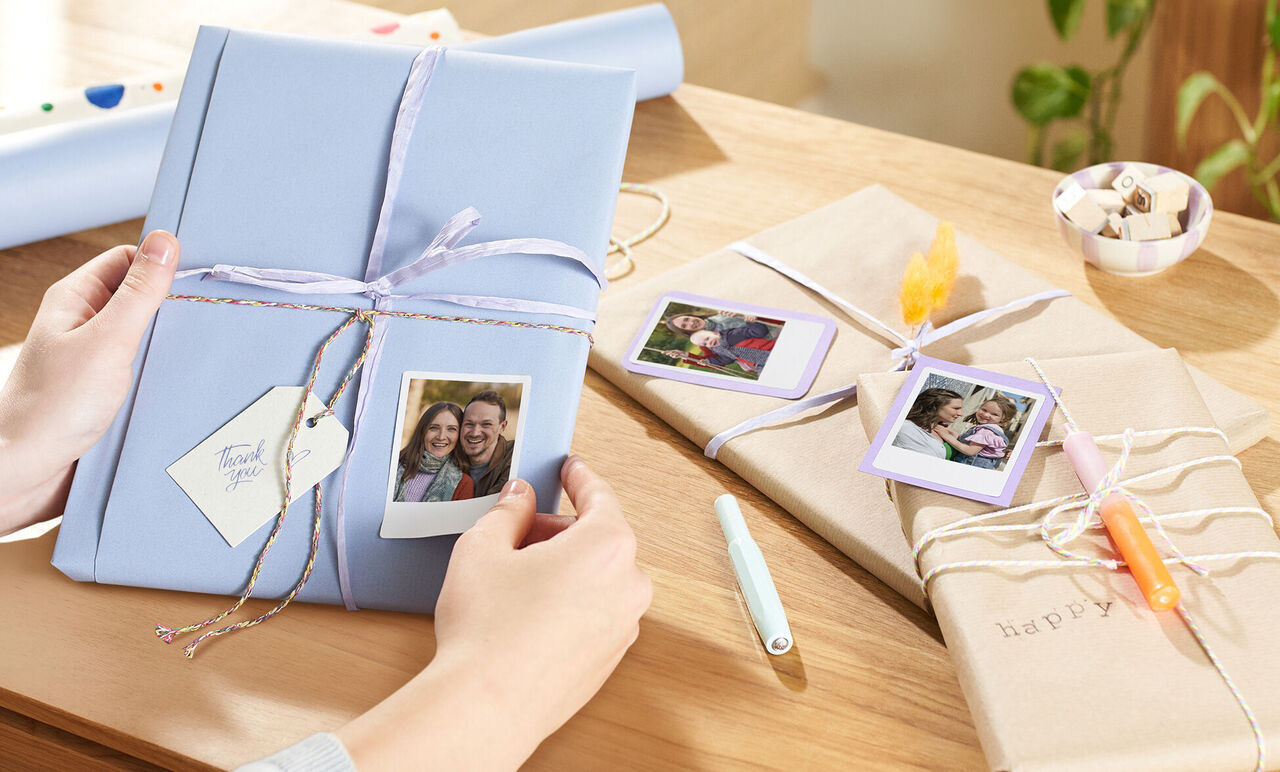 Deux jolis cadeaux emballés sur une table avec des photos et des rubans décoratifs.