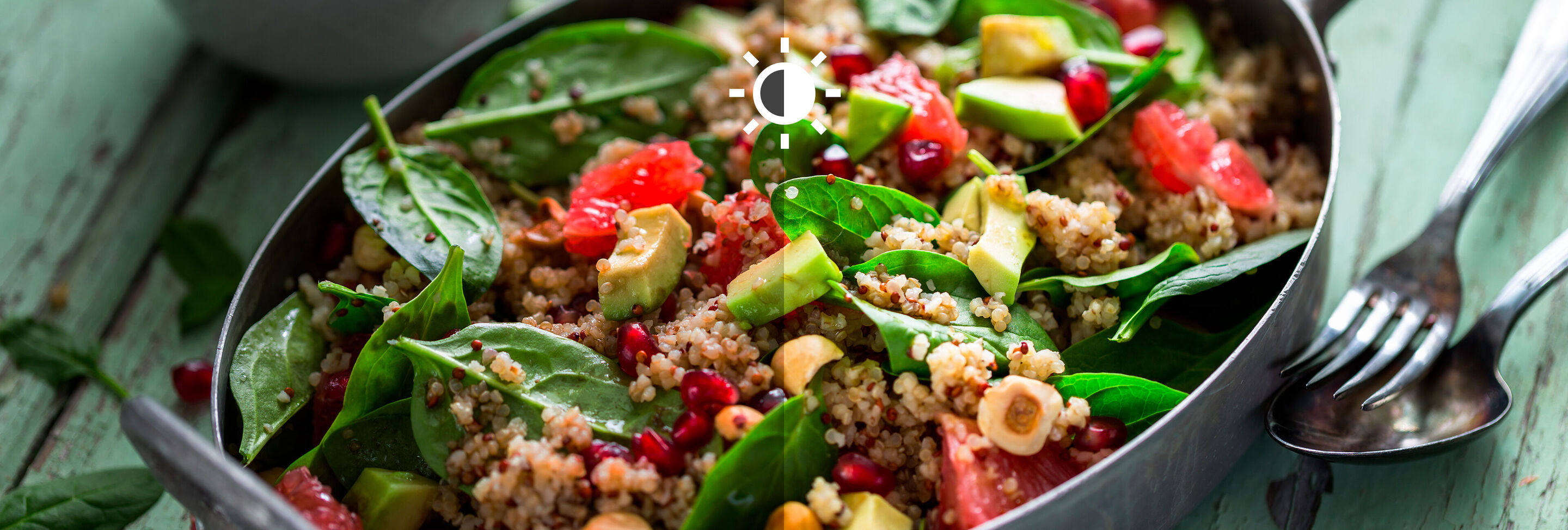 Un bol de salade de quinoa colorée avec des épinards frais, des graines de grenade et divers légumes.