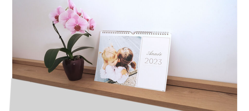 Beau calendrier 2023 avec des images d'enfants et de fleurs sur une table.