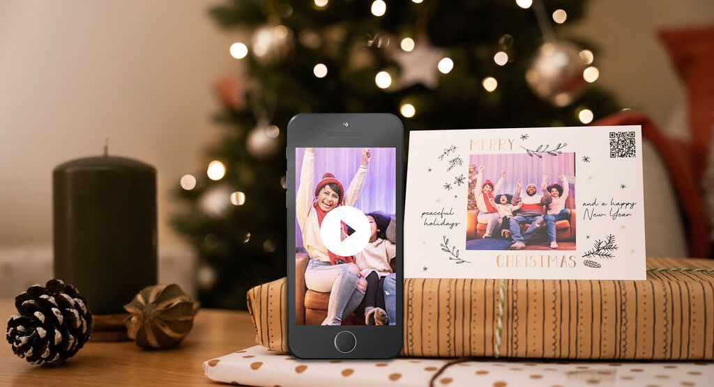 Joyeux Noël : joie avec des amis devant un sapin, une carte et un téléphone avec une vidéo.