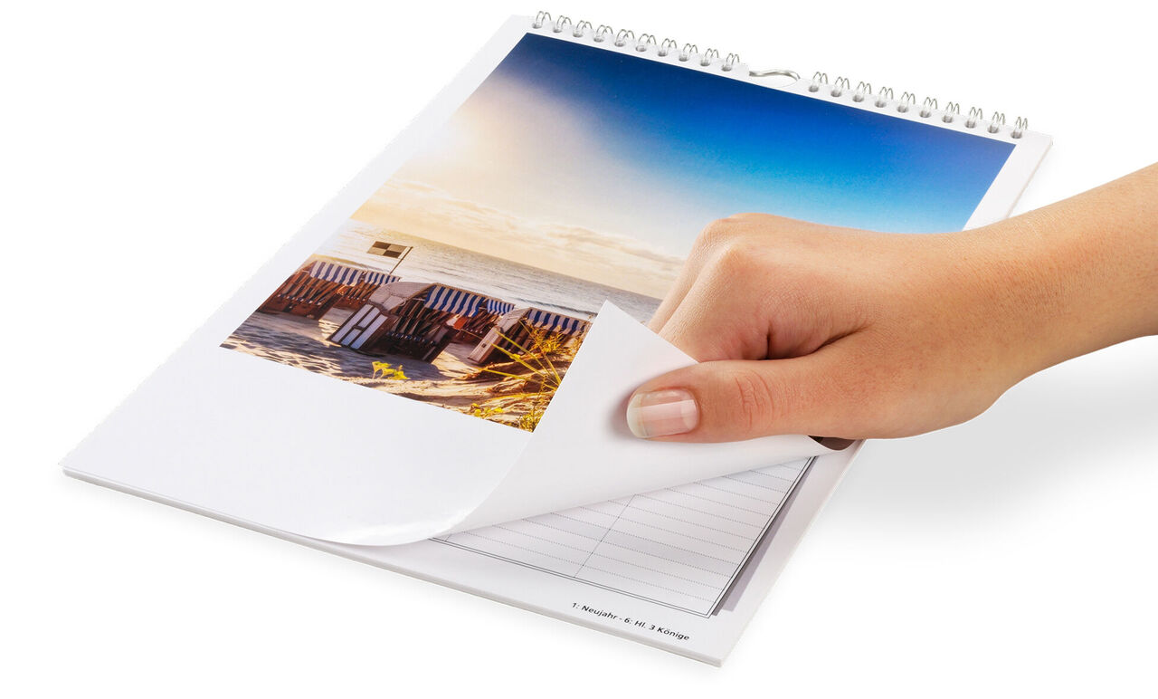 Une main tourne la page d'un calendrier photo de famille