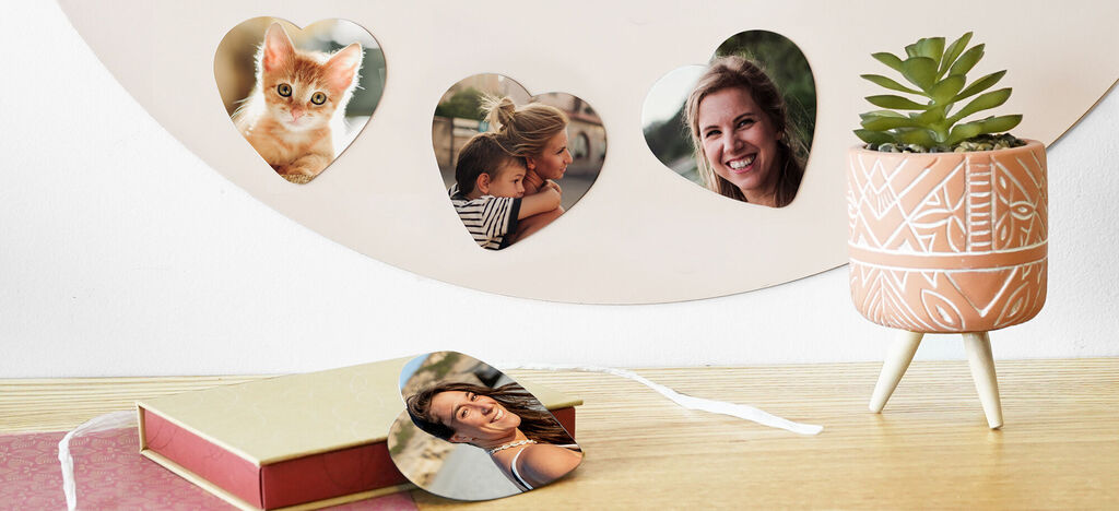 Des photos en forme de cœur pendent au mur, un livre photo et une plante moderne sont à côté.