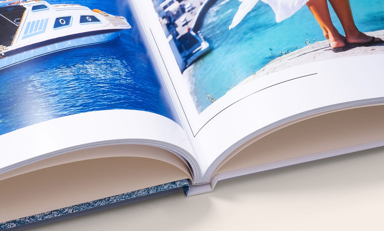 Zoom sur la reliure d'un livre photo carré XL ouvert avec de belles photos de vacances