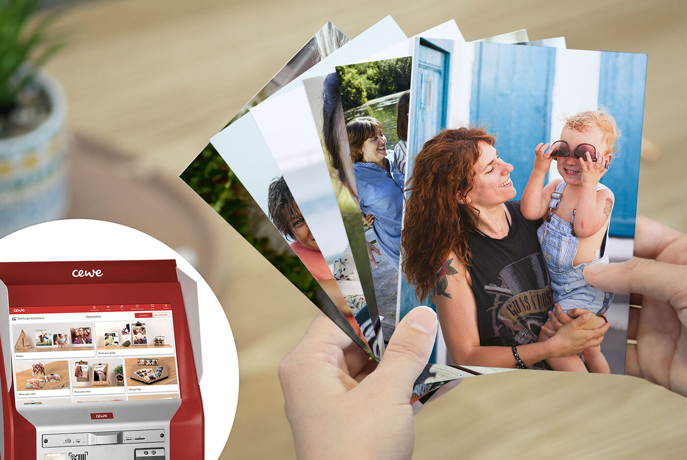Une personne tient une sélection de photos CEWE, une imprimante photo en arrière-plan.