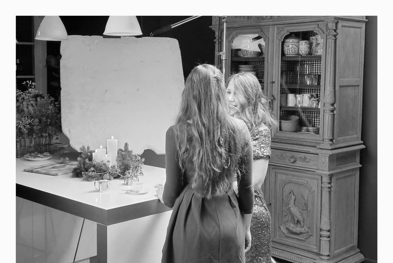 Deux femmes se tiennent à une table et sourient. Une table festive est décorée.