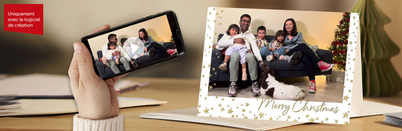 Une famille est assise sur un canapé et regarde une vidéo sur un smartphone, un sapin de Noël en arrière-plan.