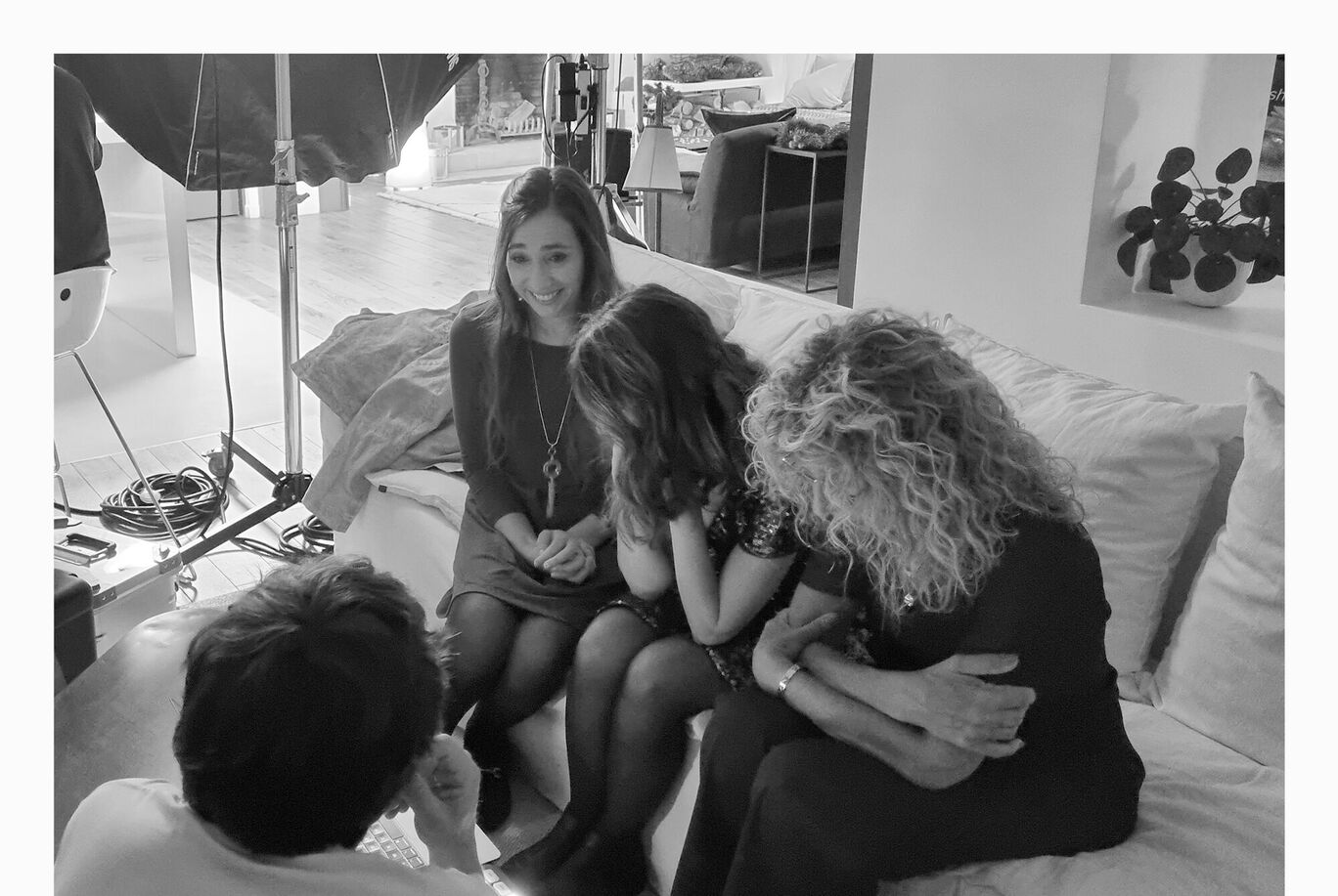 Cinq personnes sont détendues sur un canapé et rient ensemble. Il y a une ambiance joyeuse dans une pièce lumineuse.