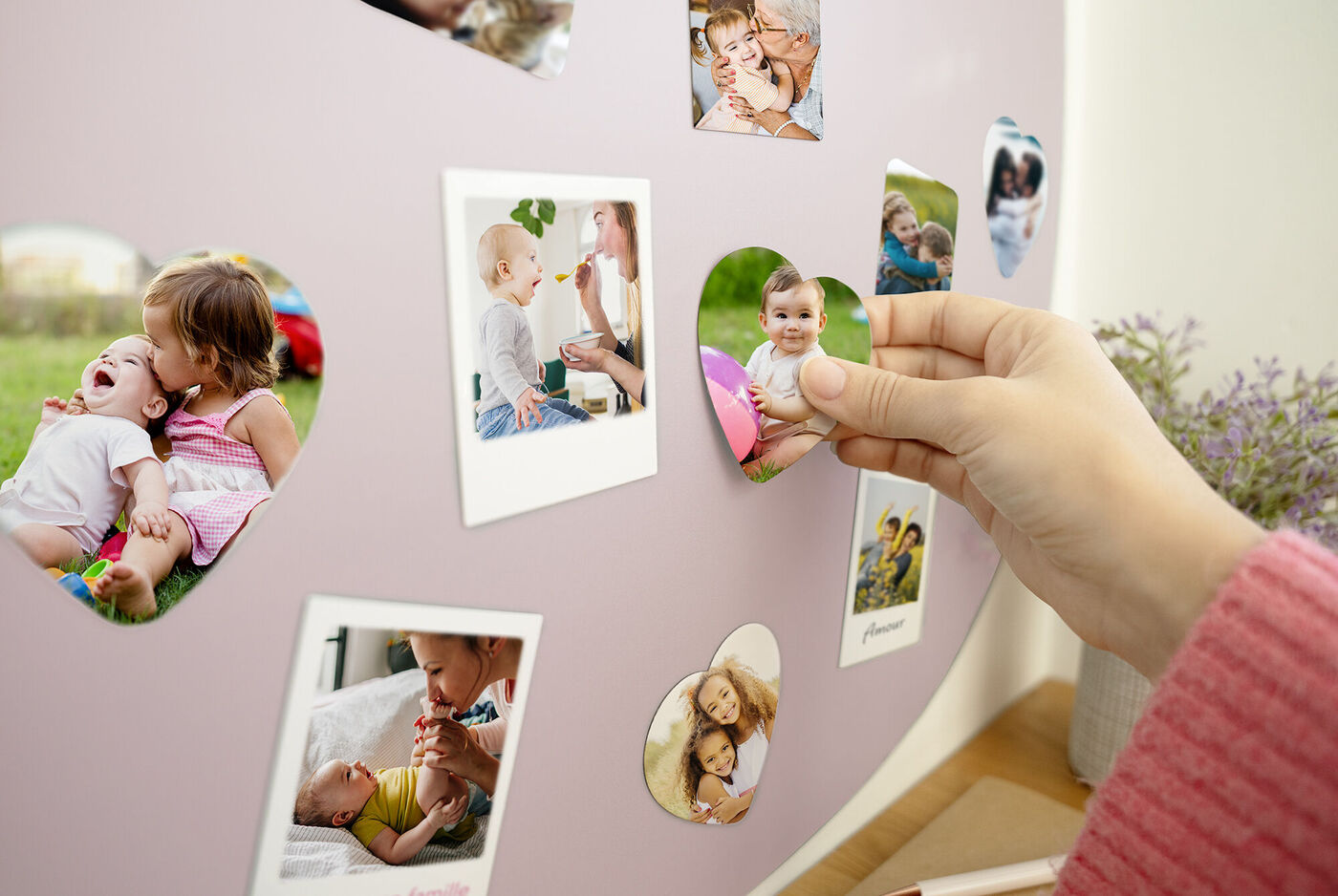 Une personne suspend des photos en forme de cœur sur un mur avec de la lavande.