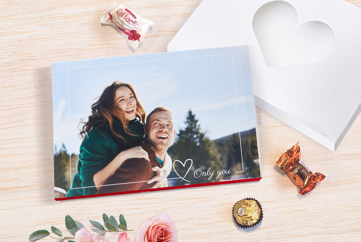 Deux personnes s'enlacent joyeusement devant un beau décor naturel avec des cadeaux et des fleurs.