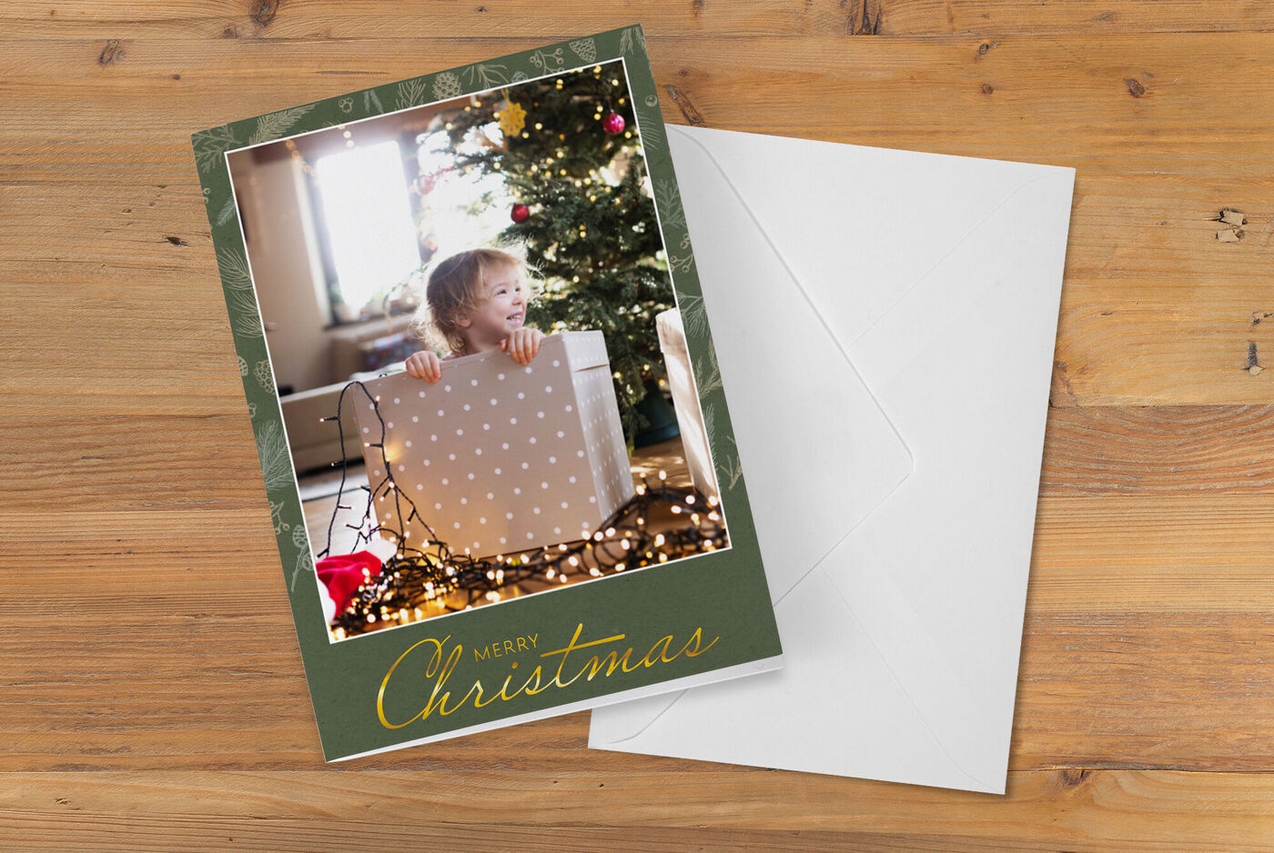 Un enfant tient un grand cadeau devant un sapin de Noël illuminé.