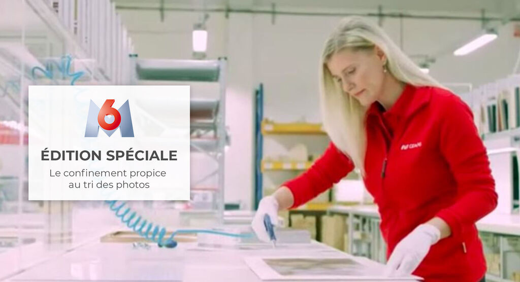 Une employée en haut rouge trie des photos sur une table.