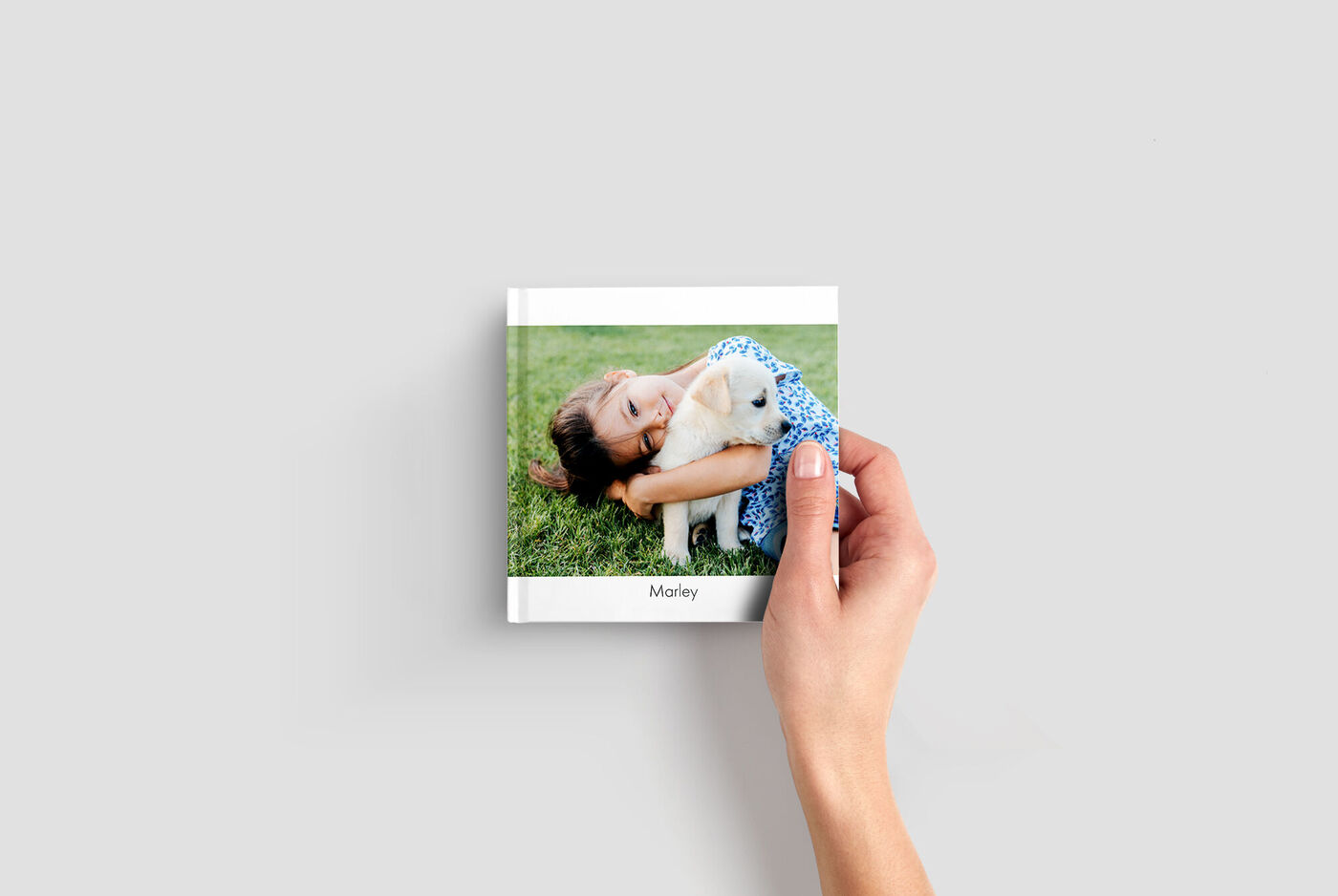 Mini album photo carré tenu dans une main