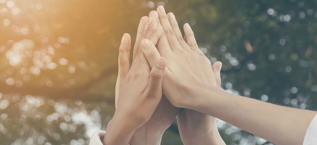 Des mains unies au soleil, exprimant la communauté et la joie.
