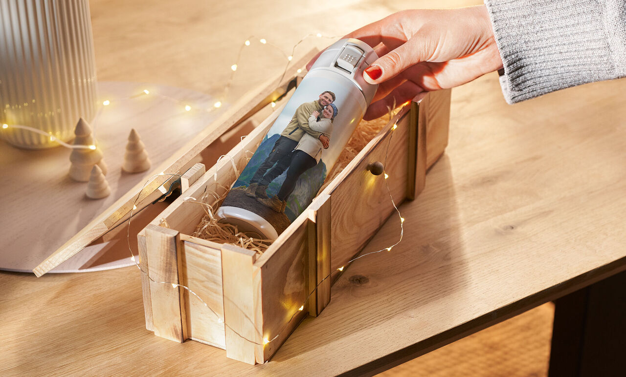 Une personne prend une bouteille d'eau personnalisée d'une boîte en bois, entourée de décoration.
