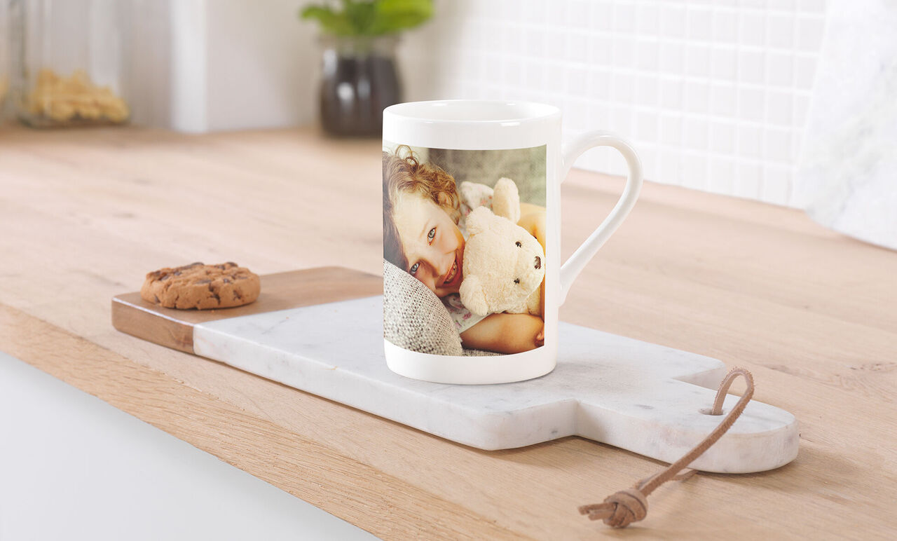 Mug en porcelaine personnalisé posé sur une table avec une photo d'une petite fille et sa peluche