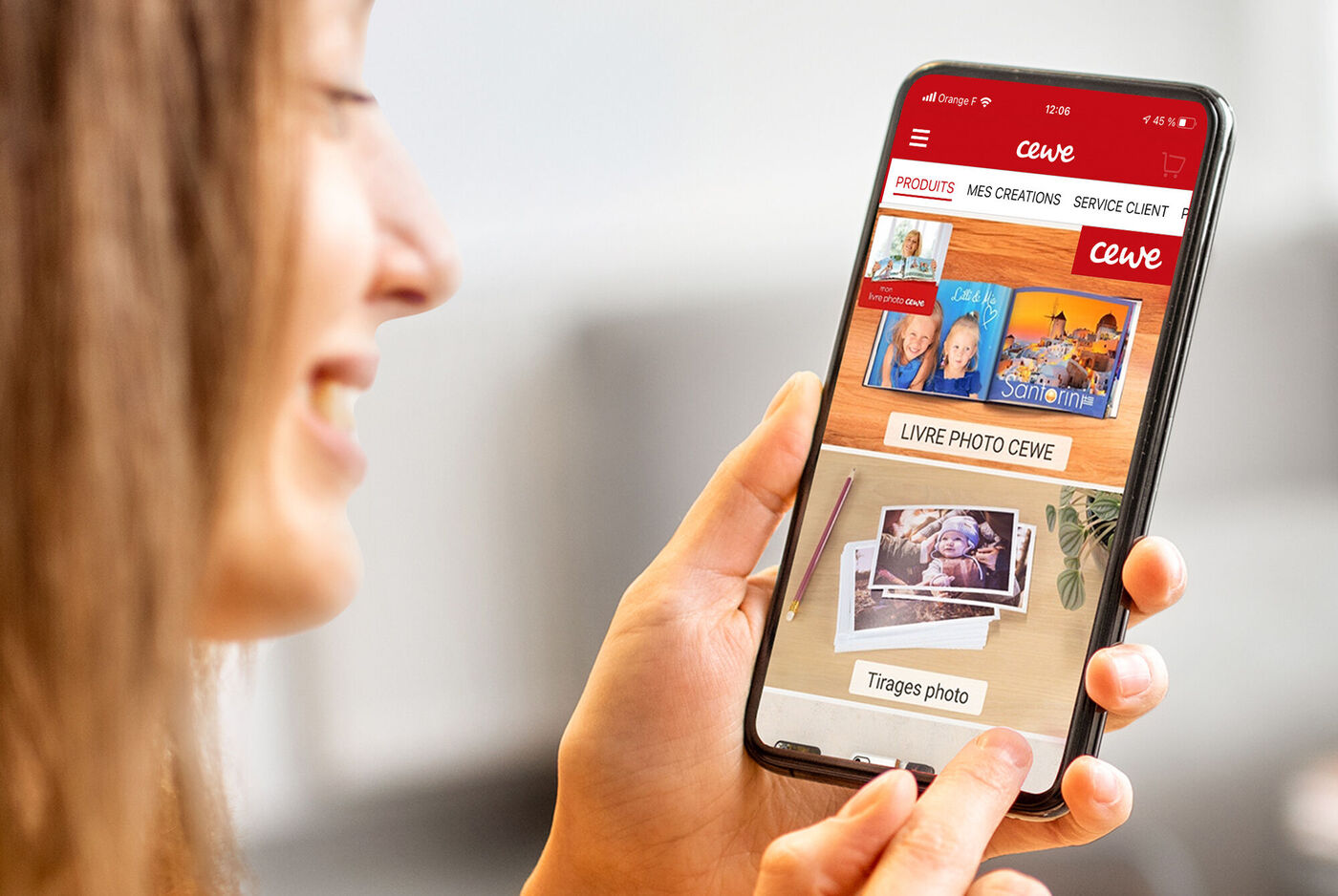 Une personne utilise l'application CEWE sur son smartphone pour voir et créer des photos.