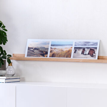 Trois photos sur une étagère en bois moderne à côté d'une plante.