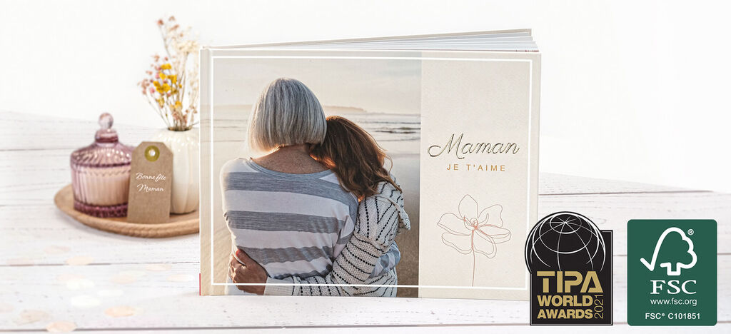 Deux femmes s'embrassent affectueusement devant un album photo créé pour maman