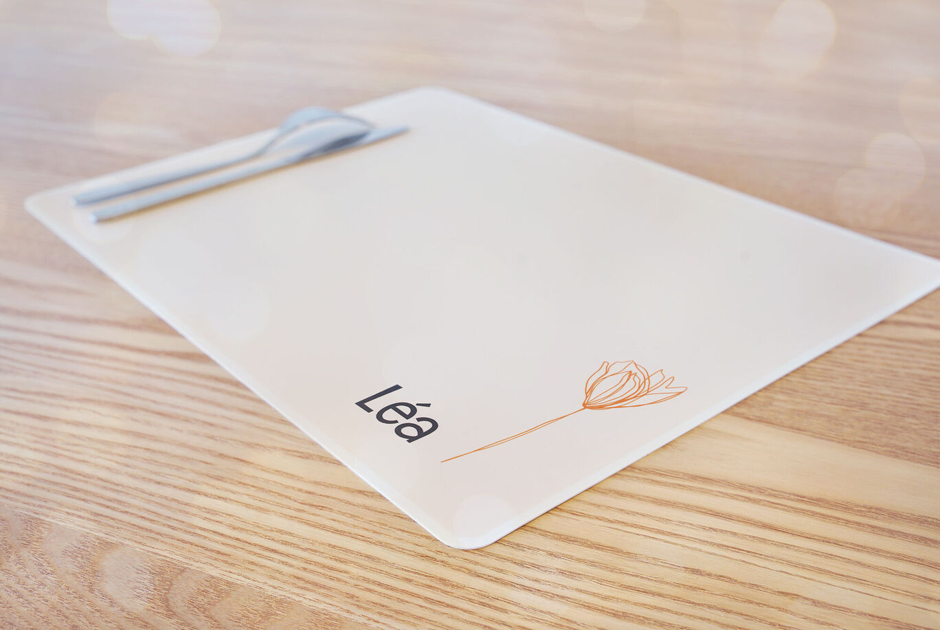 Une table joliment dressée avec une nappe. La nappe porte le nom "Léa" et une délicate fleur.