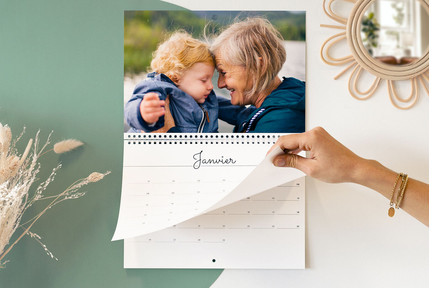 Une main feuilletant un calendrier avec une image joyeuse de deux personnes pour le mois de janvier.