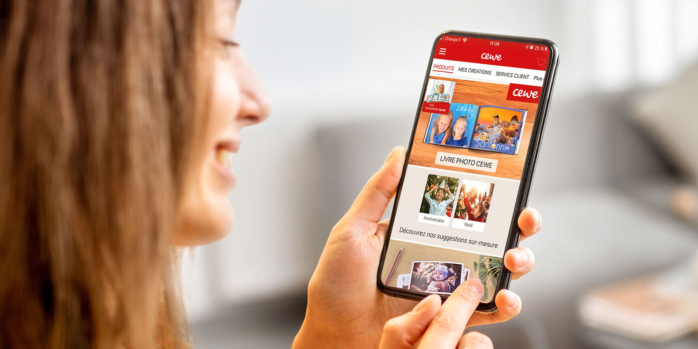 Une personne utilise l'application CEWE sur un smartphone pour voir des produits photo personnels