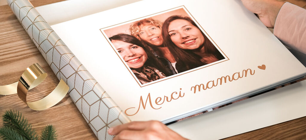 Un emballage cadeau soigneusement conçu pour un livre photo. Il montre l'inscription 'Merci maman' avec une note chaleureuse.