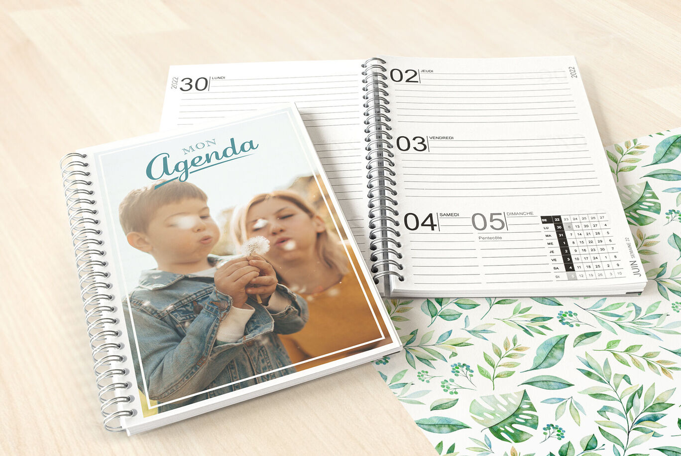 Un agenda personnel avec un beau design sur une table avec un fond de feuilles vertes.