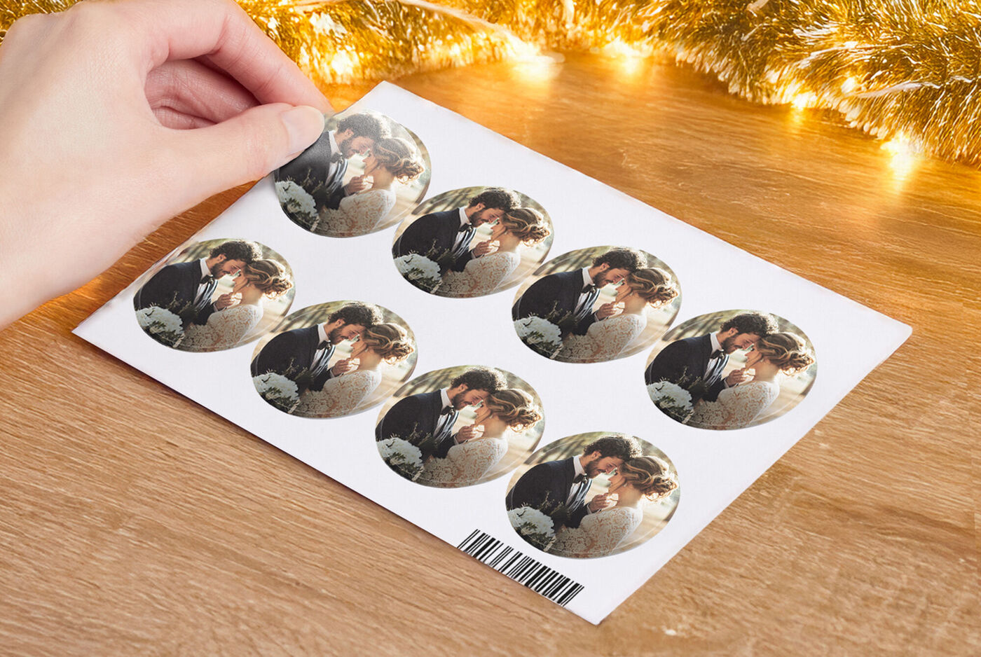 A hand holding a sheet with seven round stickers showing a couple embracing.