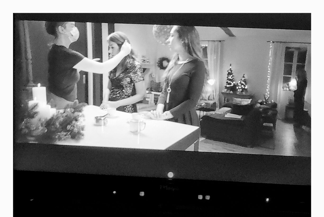 Trois femmes dans une pièce chaleureuse, une présente une décoration de Noël.