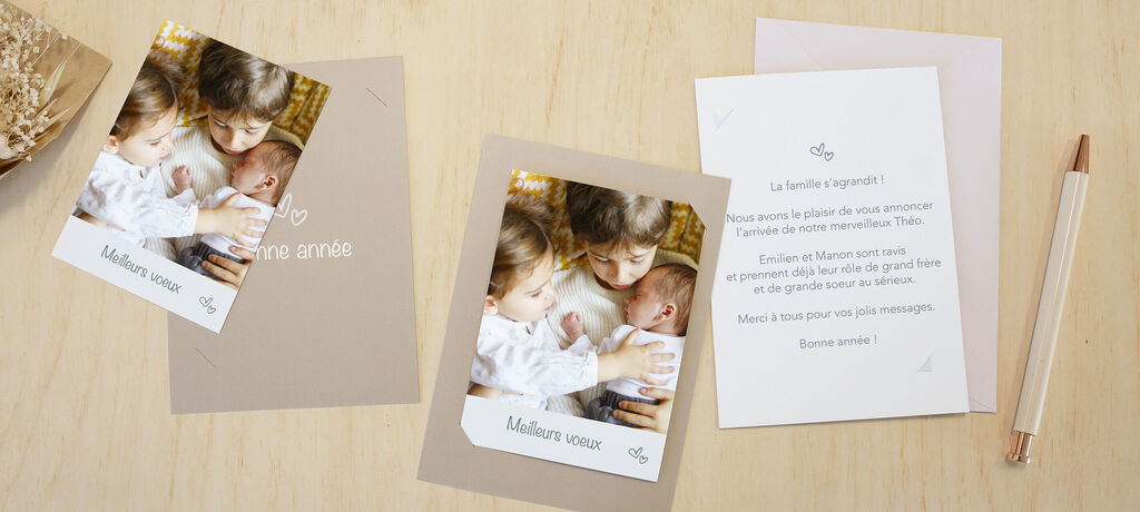Deux enfants tenant un bébé dans leurs bras et souriant. Une carte et un stylo sont à côté.