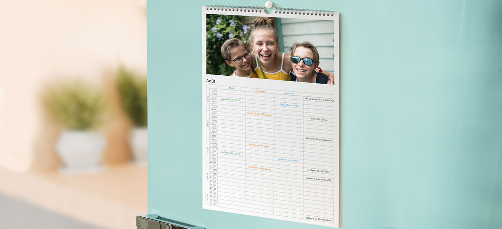 Un calendrier CEWE est suspendu au frigo, avec une image et un calendrier mensuel.