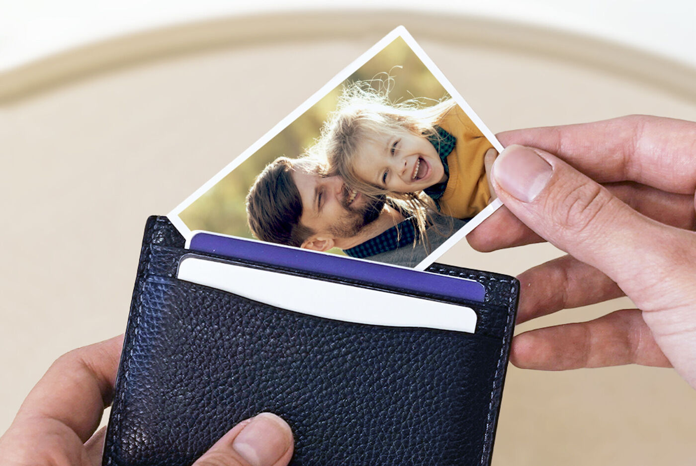 Une main tient un portefeuille noir avec une photo d'un couple qui en dépasse.