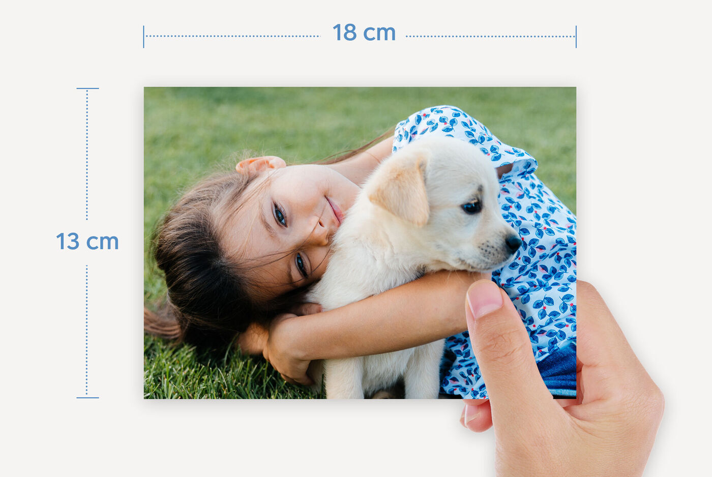 Une fille serre un chiot dans ses bras, souriant heureuse sur l'herbe verte.