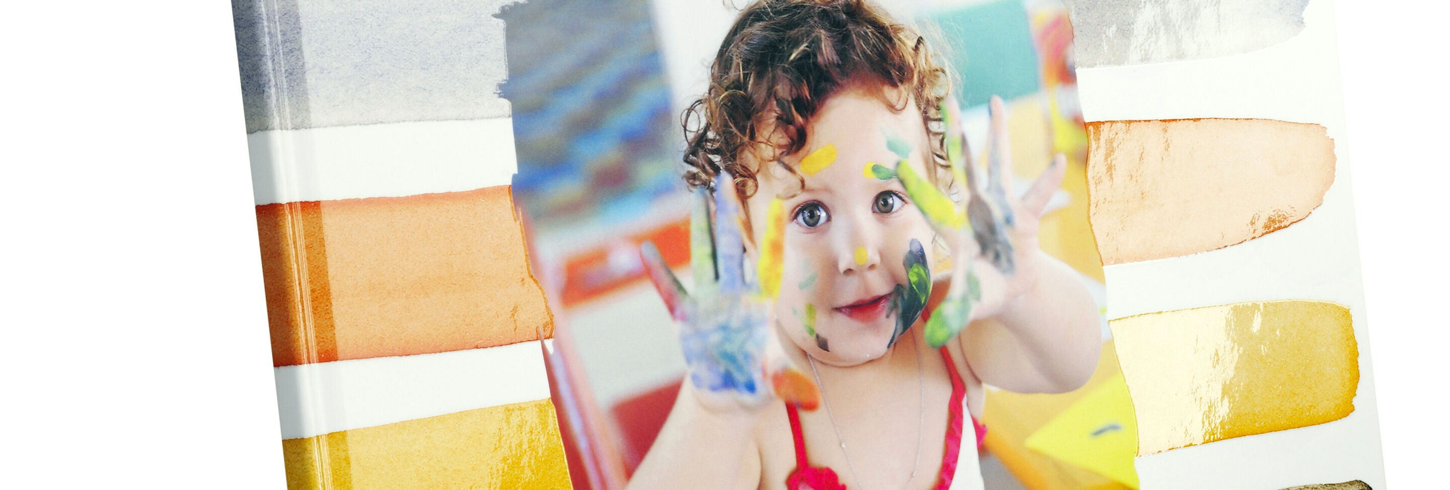 Un enfant montre fièrement un œuvre d'art créatif avec des mains colorées dans le CEWE photo livre